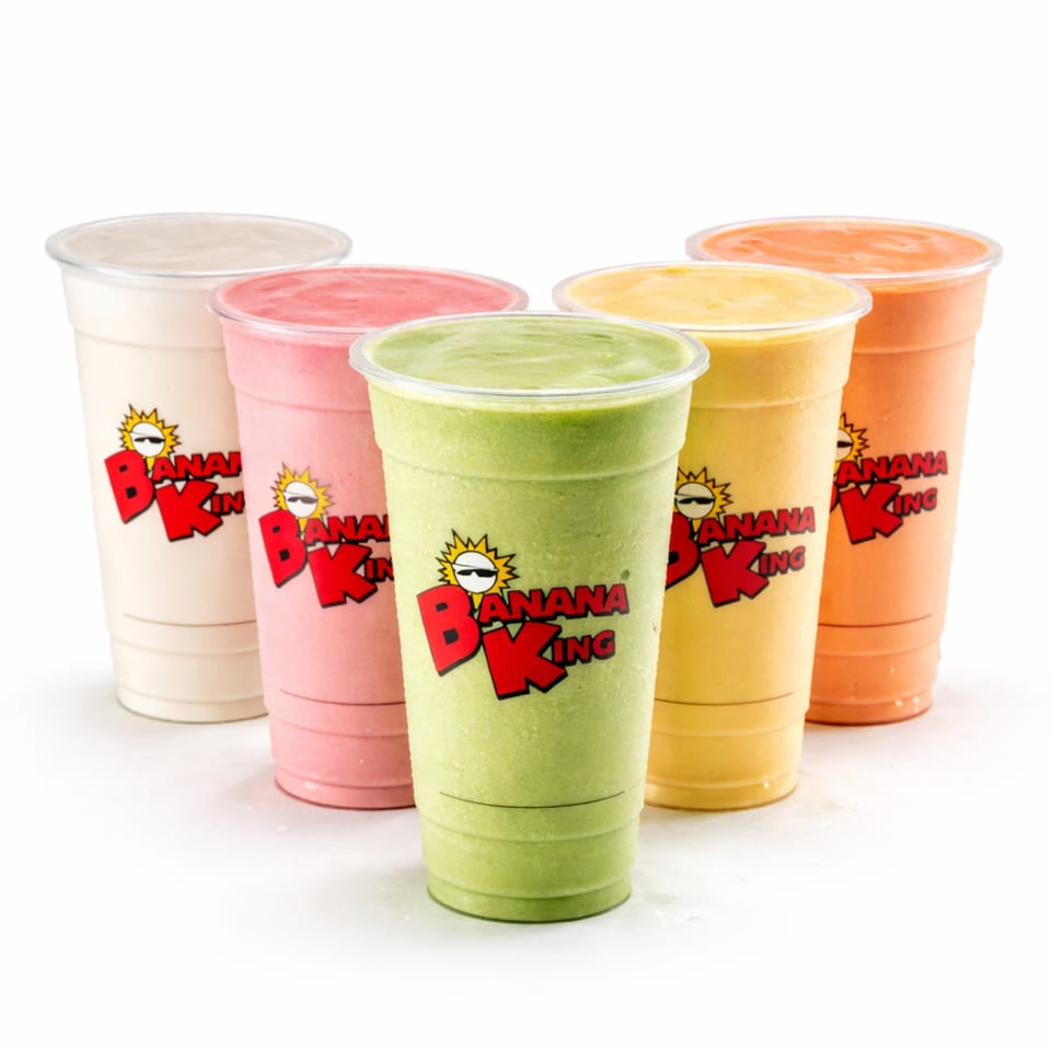 Five colorful Banana King smoothies in clear cups, featuring green, pink, yellow, orange, and cream flavors.