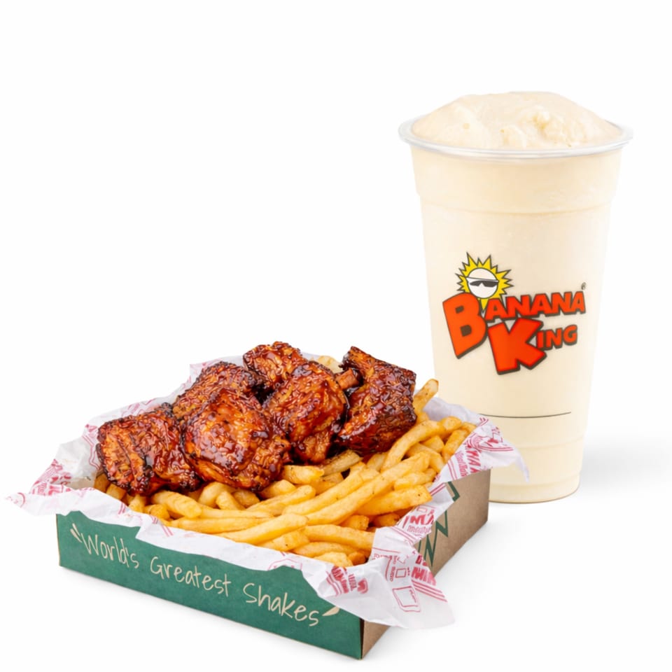 Basket of glazed chicken wings and fries beside a creamy Banana King shake in branded packaging.