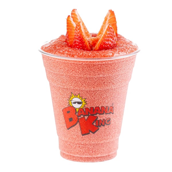 A Banana King strawberry smoothie in a clear cup, topped with fresh strawberry slices.