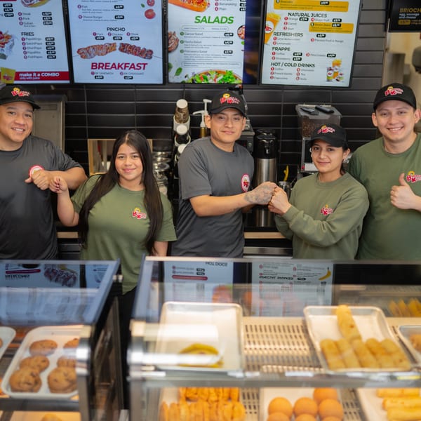 Five Banana King employees in uniform pose behind a counter with menu boards and food displays.