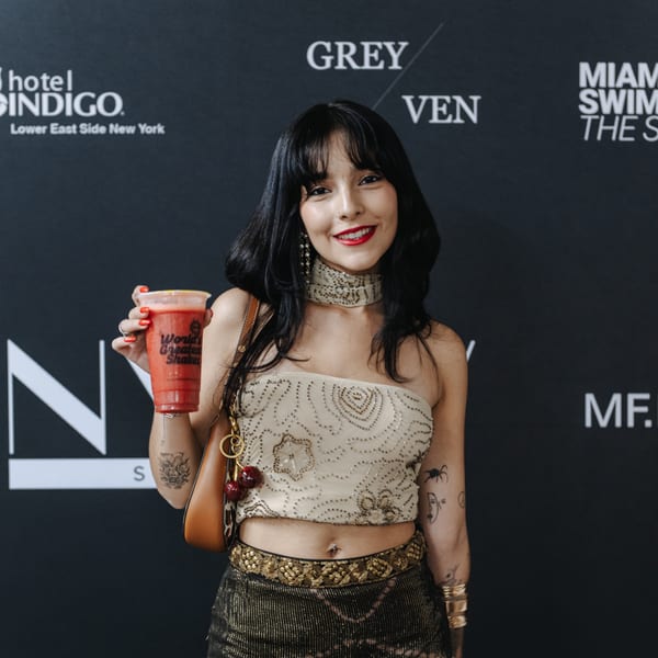 A smiling woman in a sequined top holds a red Banana King shake against a dark branded background.